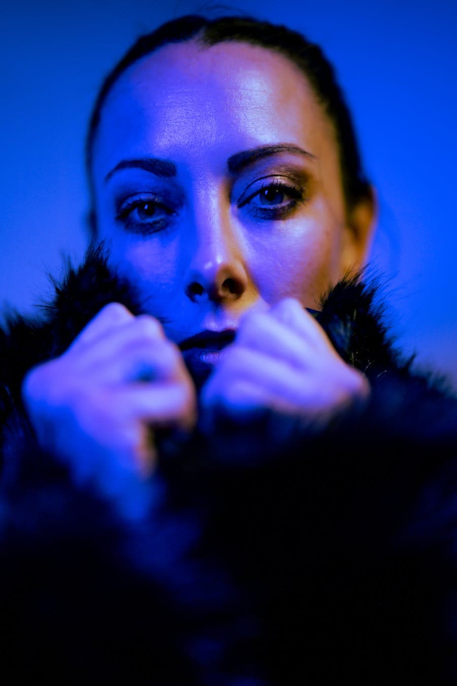 Close fashion portrait under saturated blue light.